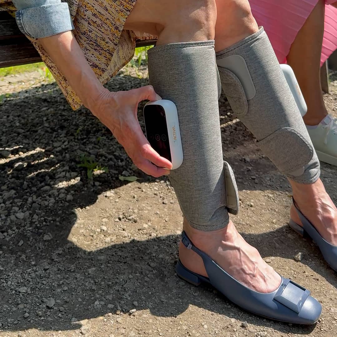 Moteris lauke naudoja CompreLax blauzdų masažuoklį su valdymo pultu ant kojos